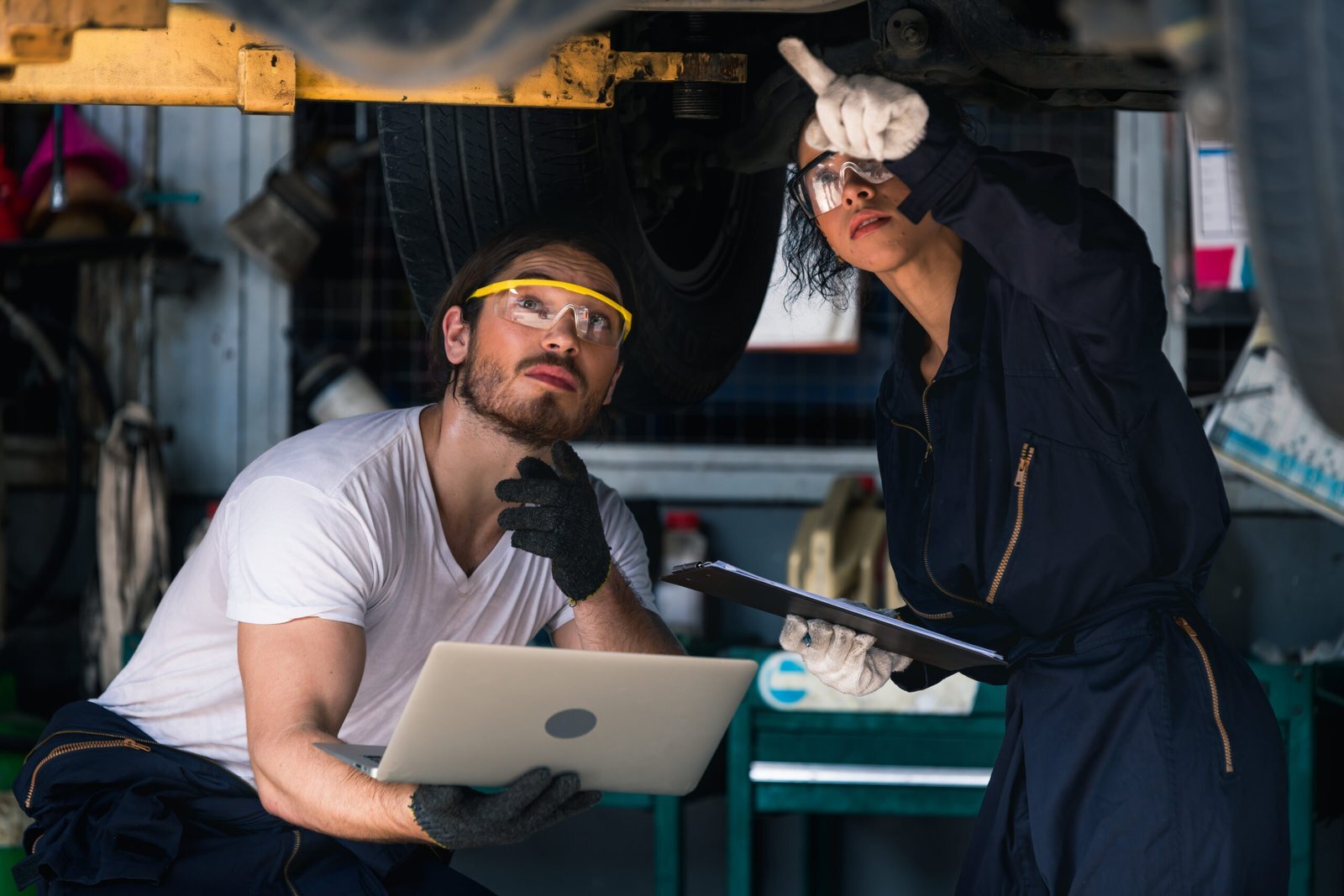 Deux mécaniciens collaborent lors d’un contrôle sous un véhicule, combinant technologie et expertise.