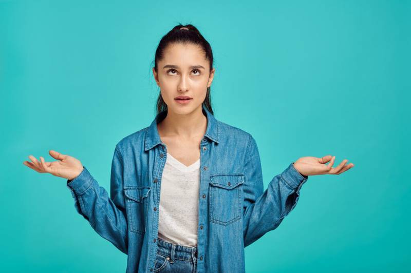 Jeune femme confuse levant les mains, symbole d'incertitude face à un problème.