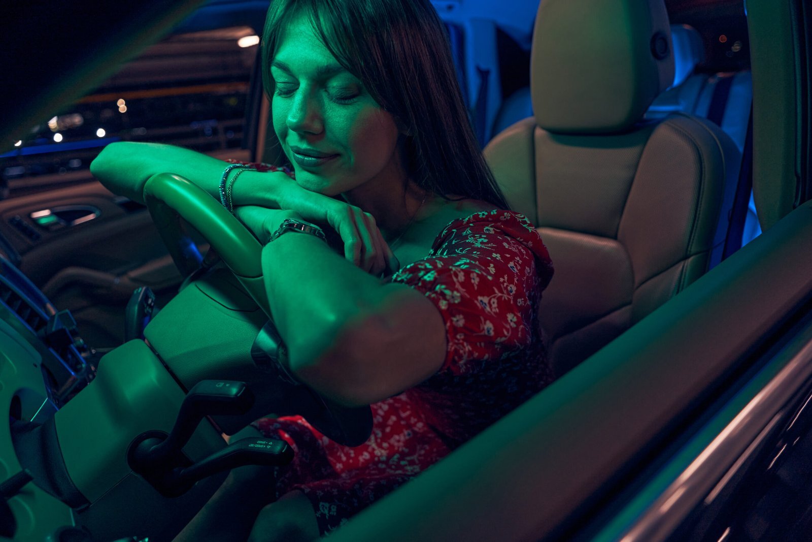 Une conductrice détendue, assise dans sa voiture, ferme les yeux et repose sa tête sur le volant.
